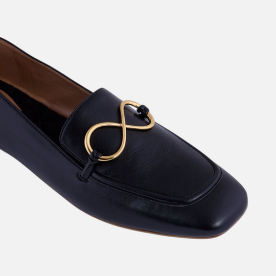 Mocassin AERA ELLA effet nappa noir, gros plan de l’ornement doré en forme d’infini et du bout arrondi.