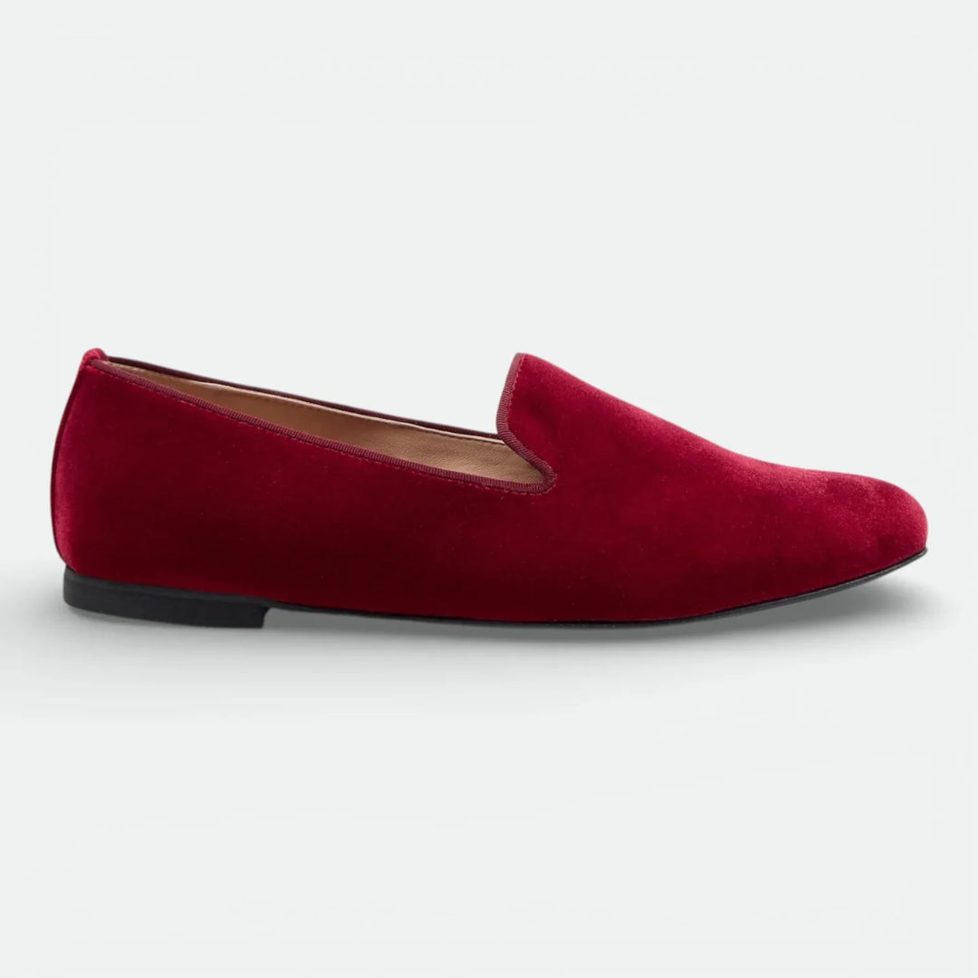 Red velvet loafer shoe with low black sole, classic slip-on design, side profile view