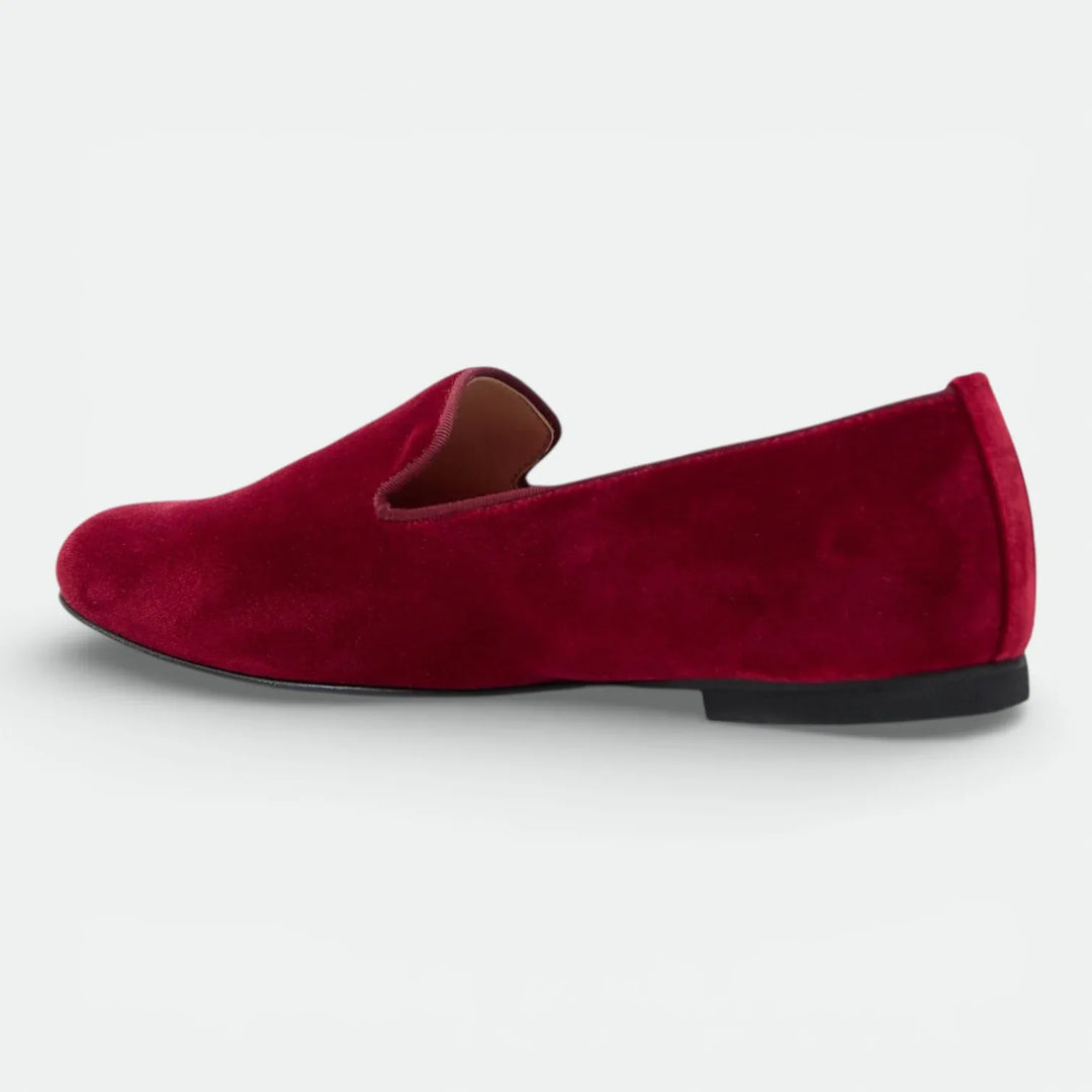 Red velvet loafer shoe with low black heel, side view on white background