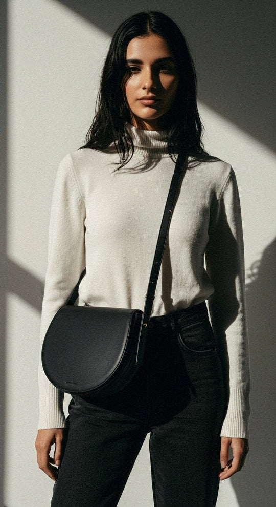 Model wearing Sofi | Midi Crossbody Bag | Black by ALEXANDRA K. VEGAN HANDBAGS from ALLTRUEIST, featuring a sleek half-moon design.