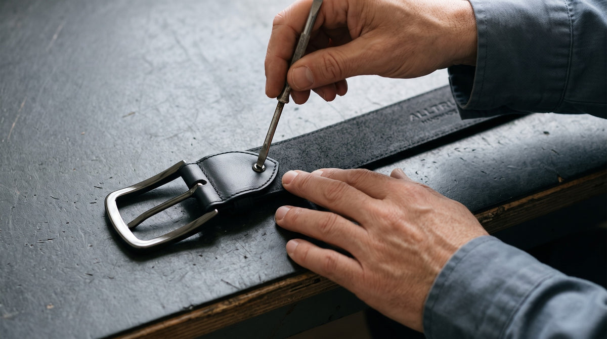 Mains fixant la boucle d’une ceinture noire sur un établi.