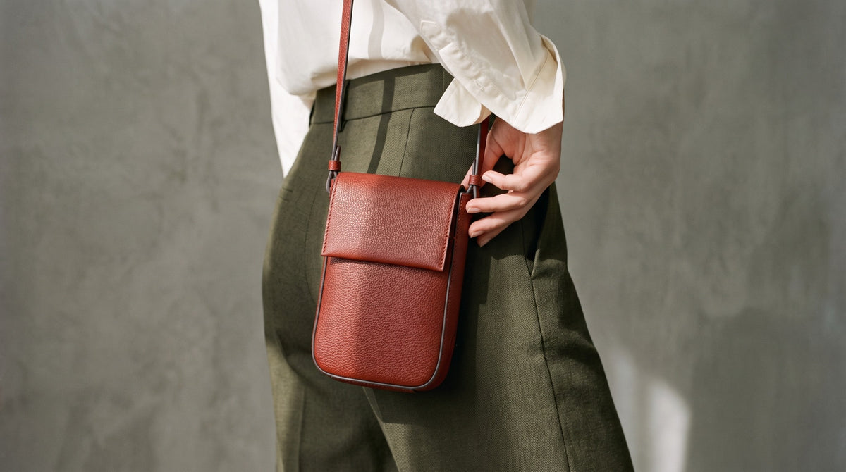 Femme portant un sac bandoulière Two.B terracotta avec un pantalon olive et une chemise ivoire.